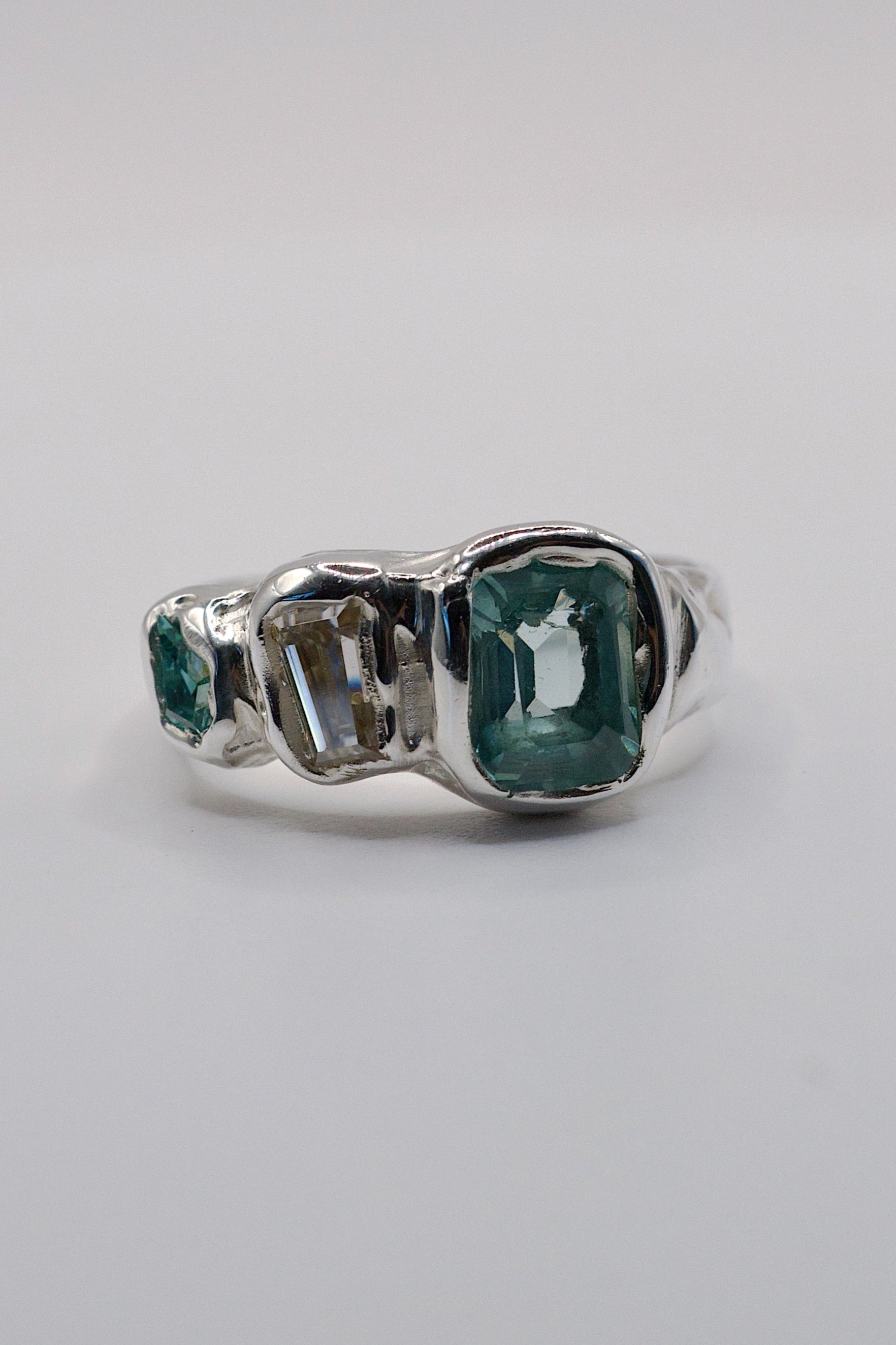 Handmade lost wax cast sterling silver ring with aqua tourmaline, white moissanite and green moissanite set within flowing molten silver, ocean inspired sculptural ring made using the wax carving technique