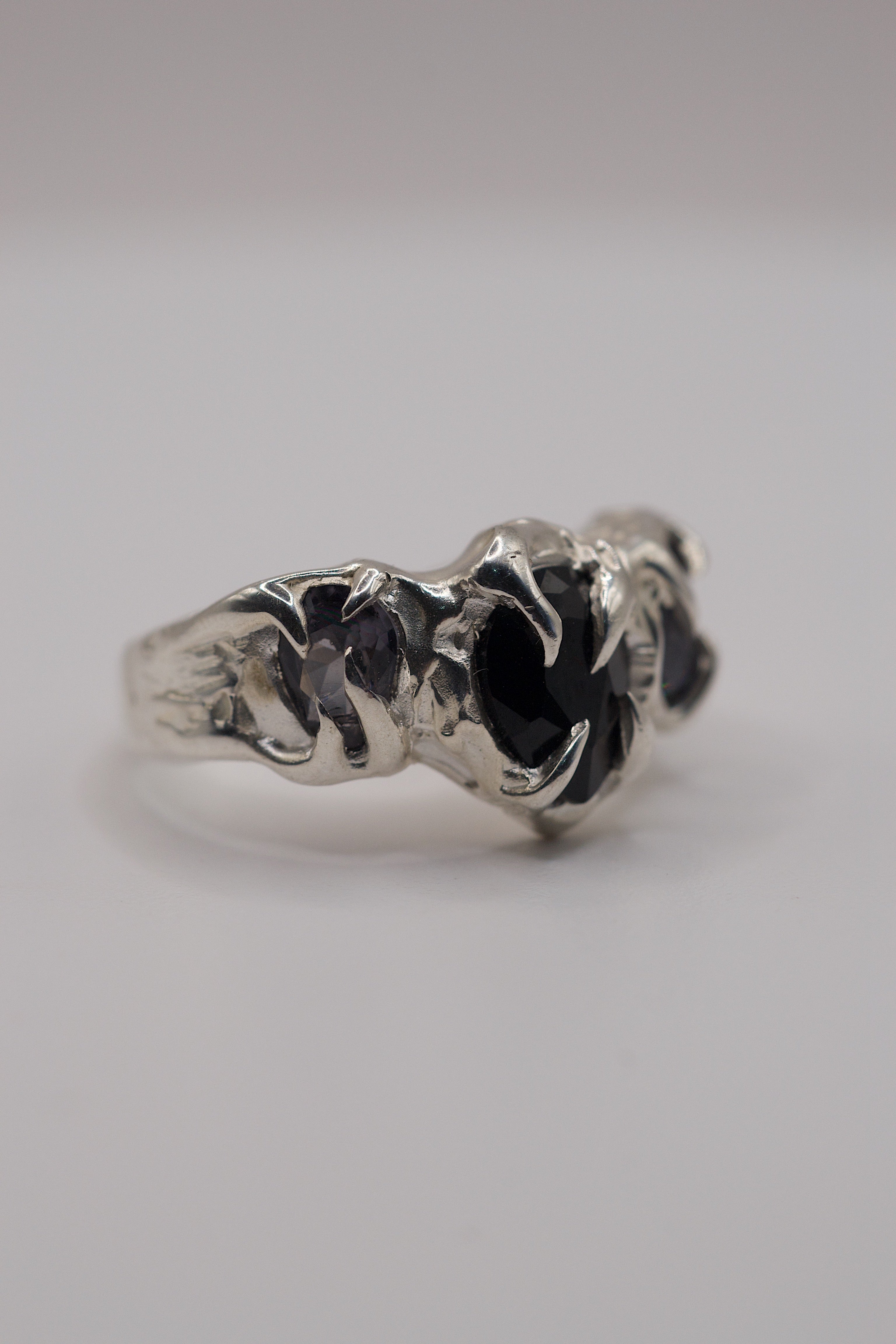side view of sterling silver organic handmade ring with grey and black lab-grown pear-cut gemstones.
