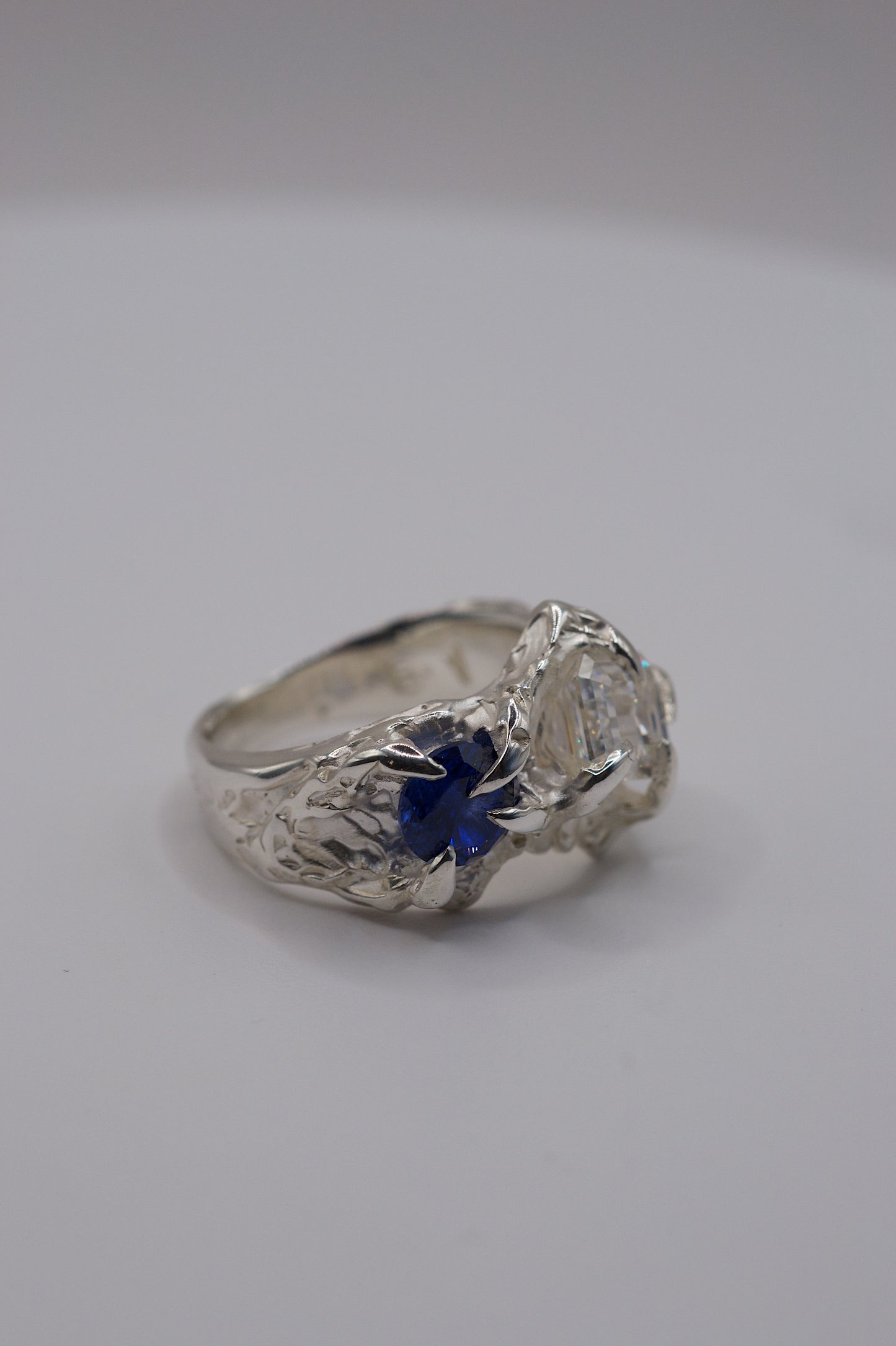Sterling silver ring side view with four gothic claws and a natural deep blue round sapphire.