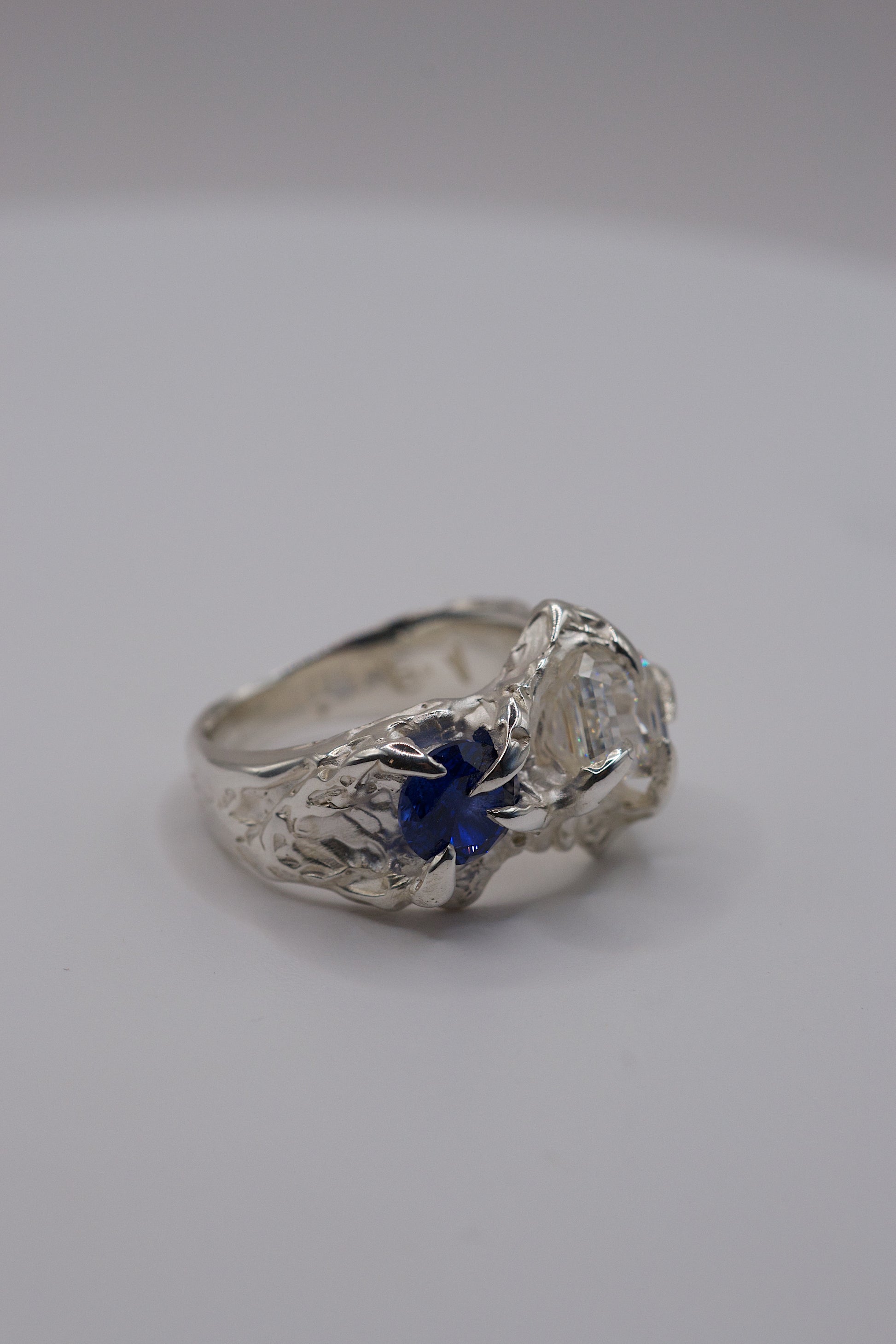 Sterling silver ring side view with four gothic claws and a natural deep blue round sapphire.