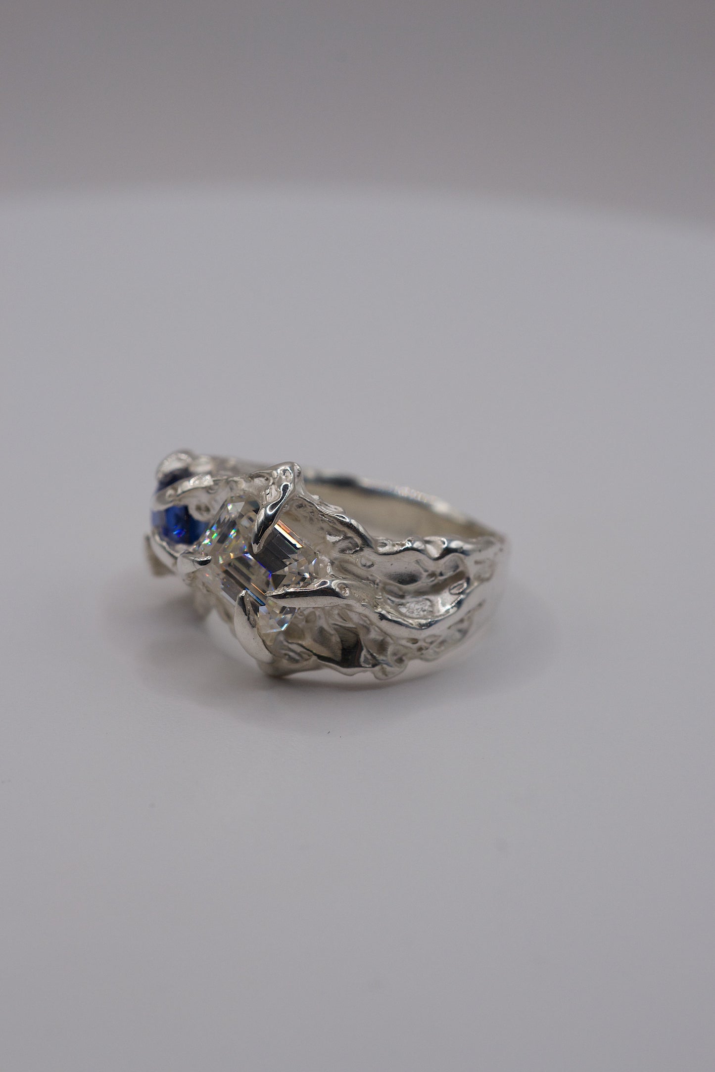 Side view of handmade sterling silver lost wax ring with view of emerald-cut radiant moissanite.