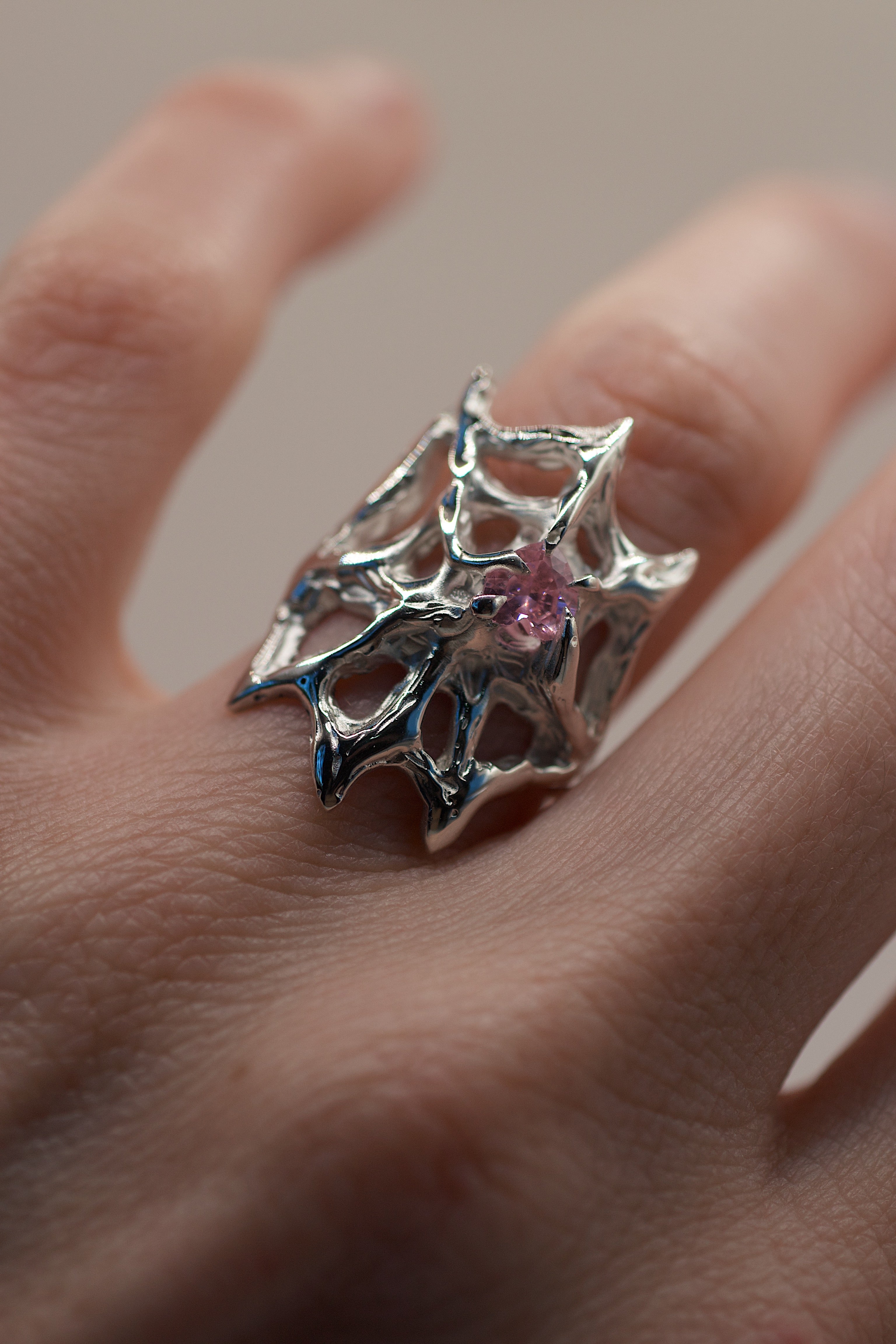 Lost wax cast silver Silk Ring worn on hand close up showing open web structure and pink heart cubic zirconia feminine gothic alternative jewellery