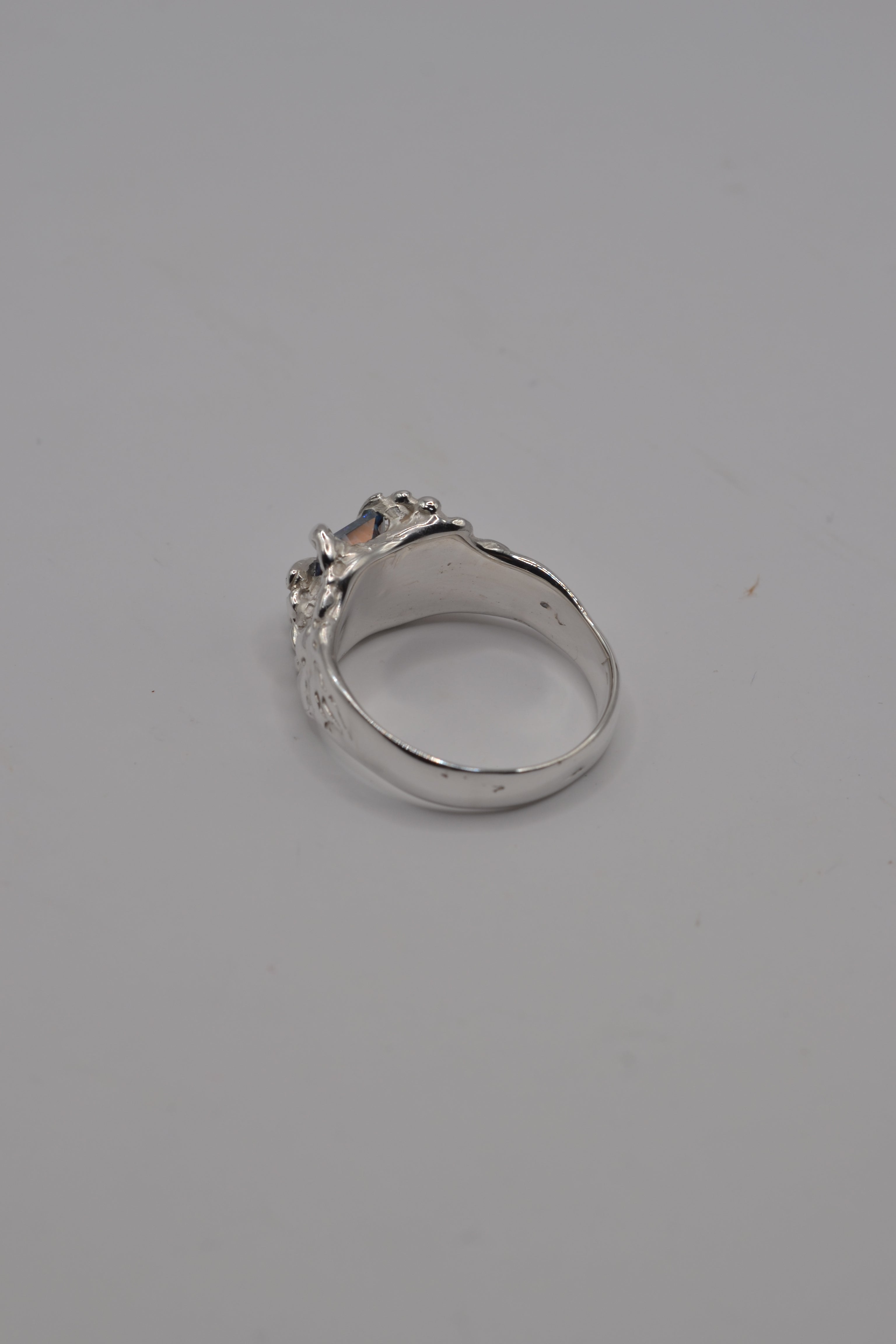 Side angle of the lost wax cast Starburst Ring showing organic sculptural sterling silver band and blue moissanite setting