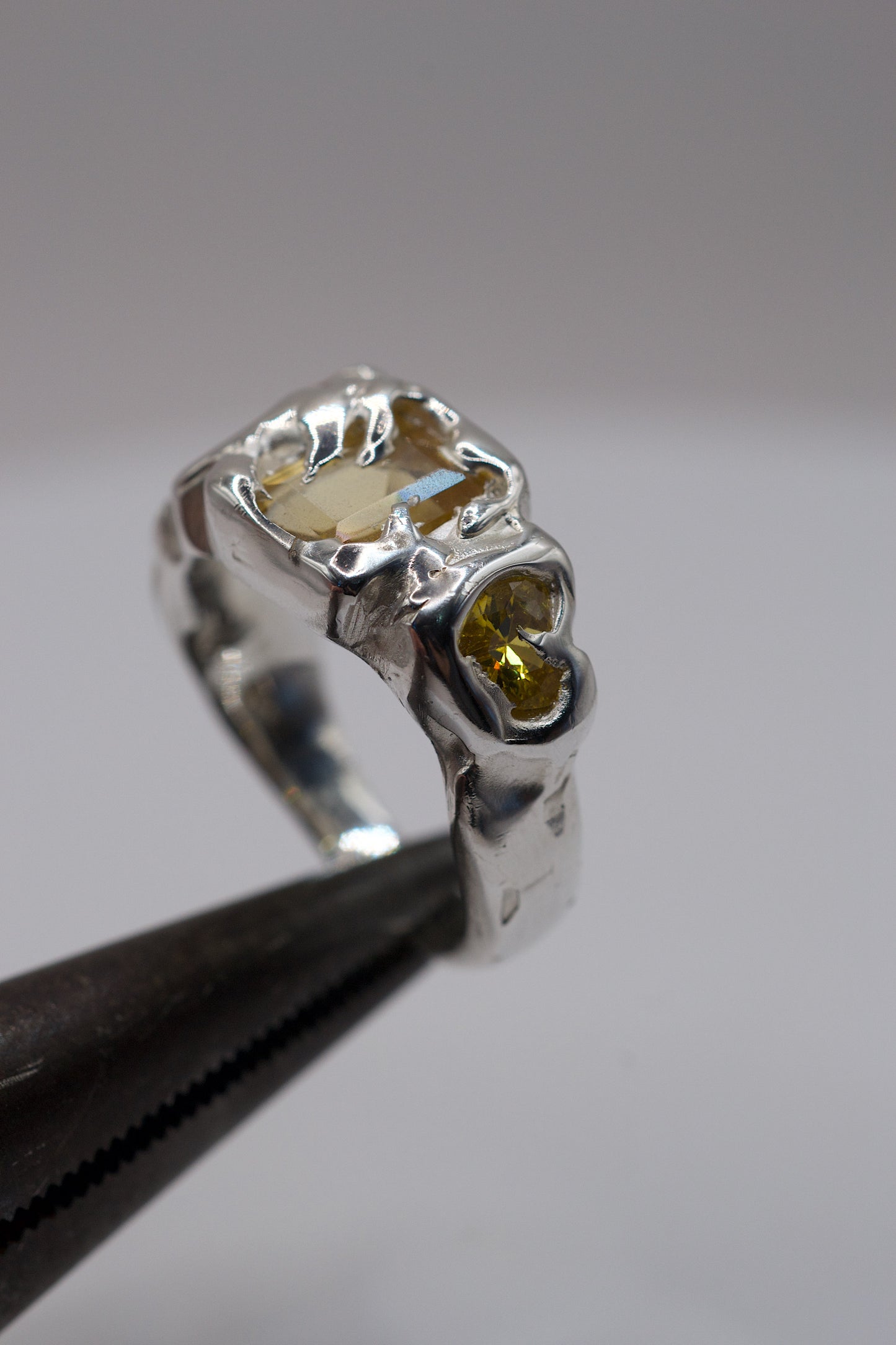 Sterling silver molten ring with yellow gemstones on pliers