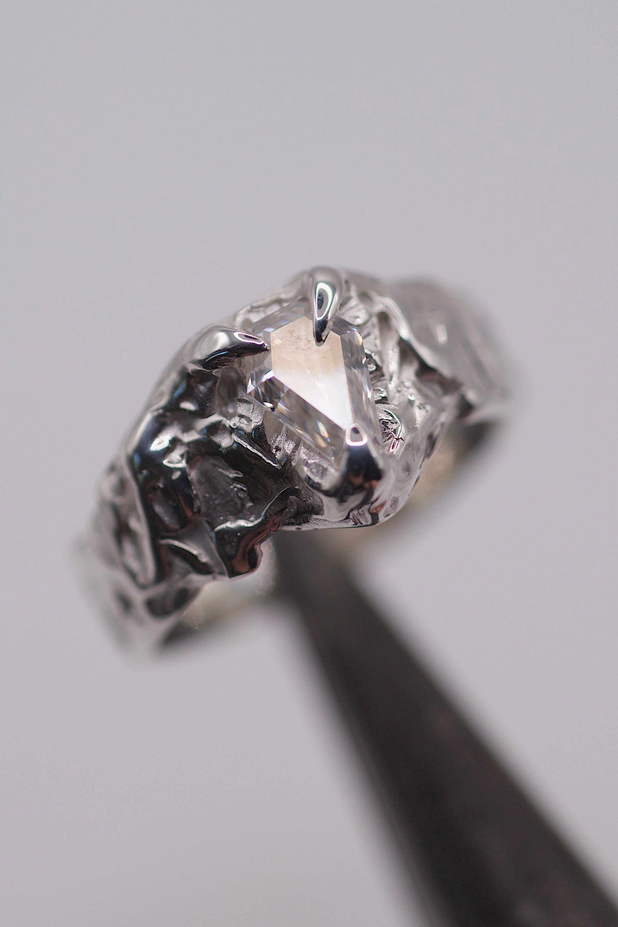 Handmade lost wax cast sterling silver ring with molten textured setting holding a kite cut moissanite, sculptural alternative engagement ring made using the wax carving technique