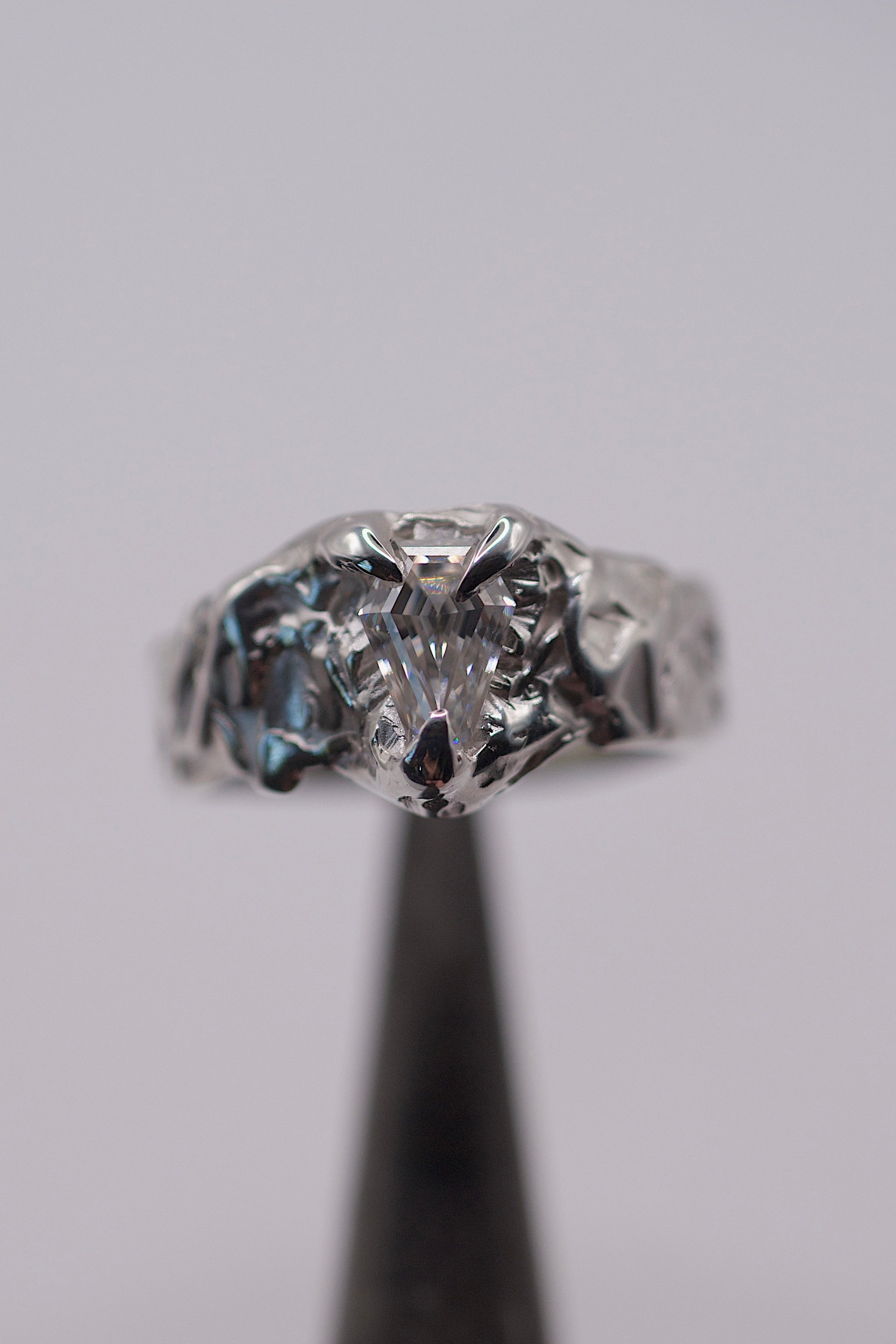 Til Death Ring held in tweezers showing kite cut moissanite set within organic heavily textured recycled sterling silver handmade using the lost wax technique