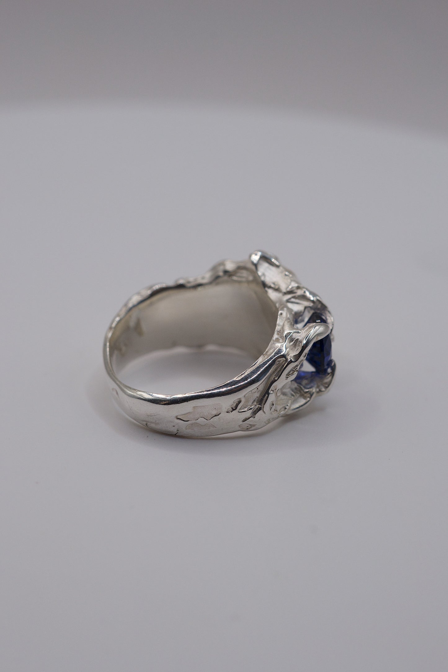 Top view of organic sterling silver ring with sapphire and moissanite with a textured band.