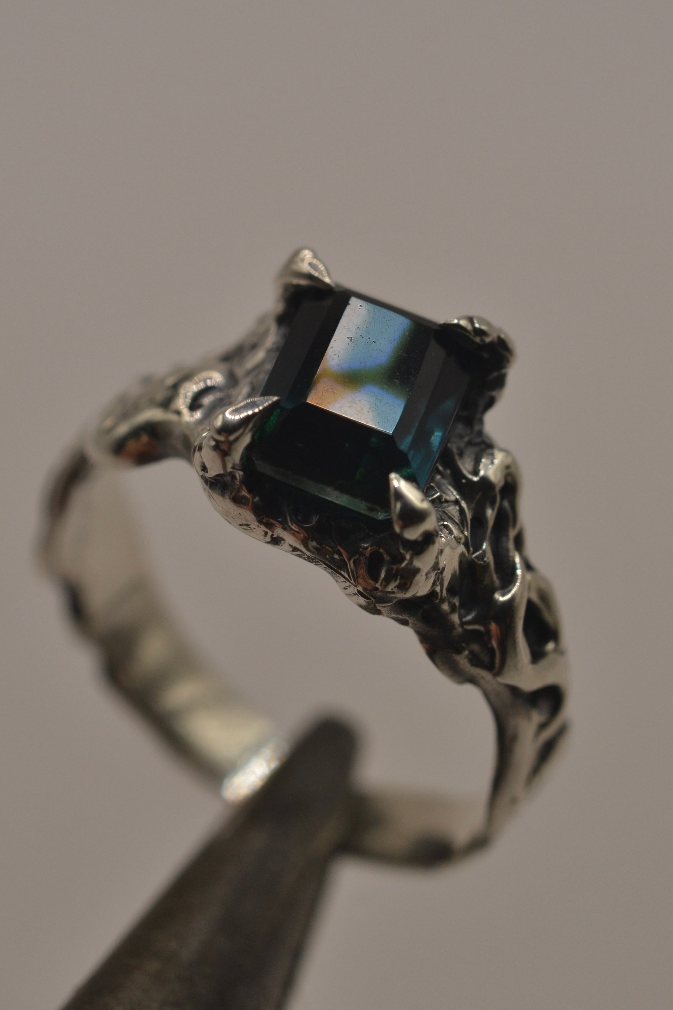 Side angle of the Twilight Ring showing organic darkened recycled sterling silver band and teal sapphire setting handmade using lost wax casting