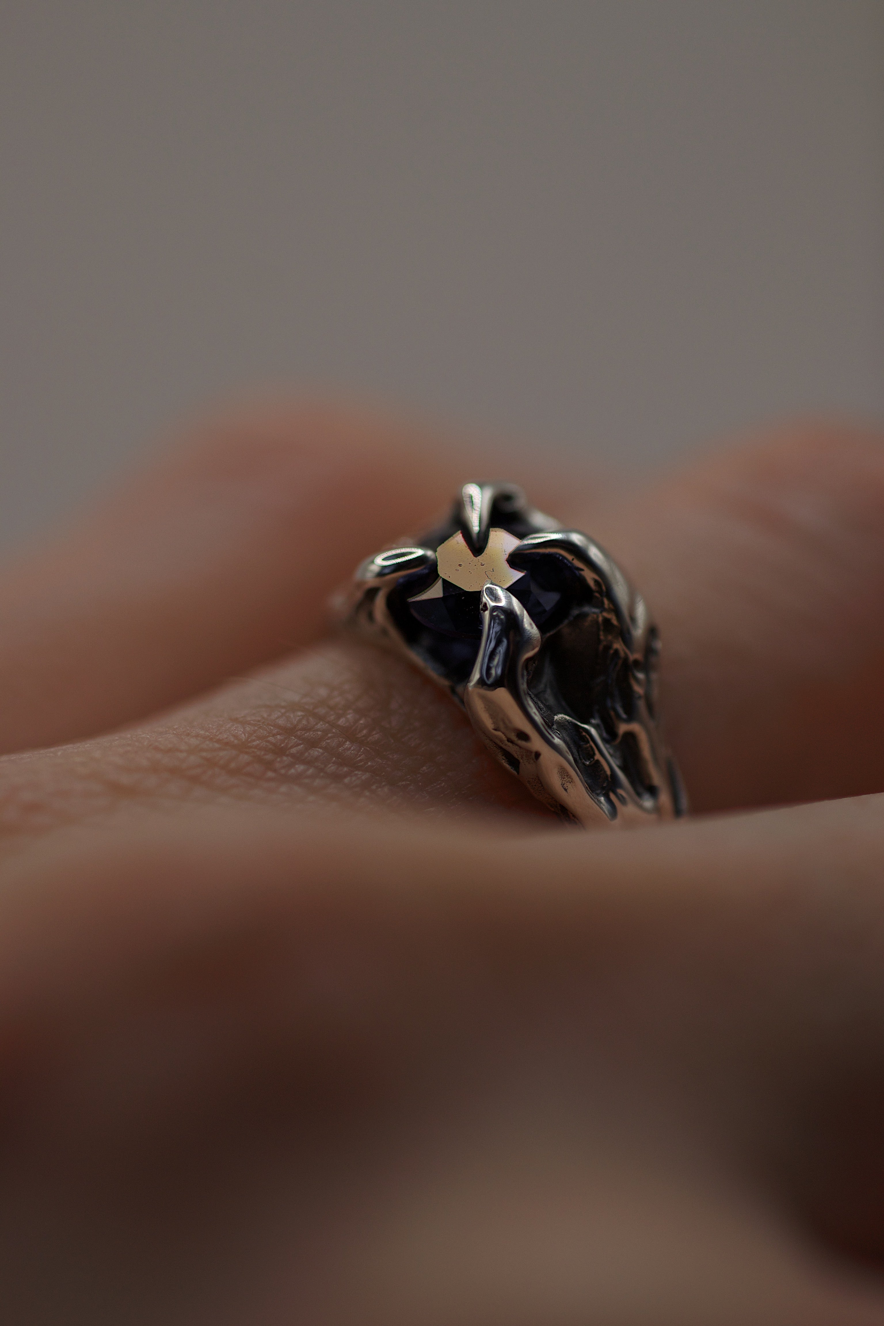 Lost wax cast darkened sterling silver Volcanic Ring worn on hand with deep blue natural sapphire and organic molten claw setting