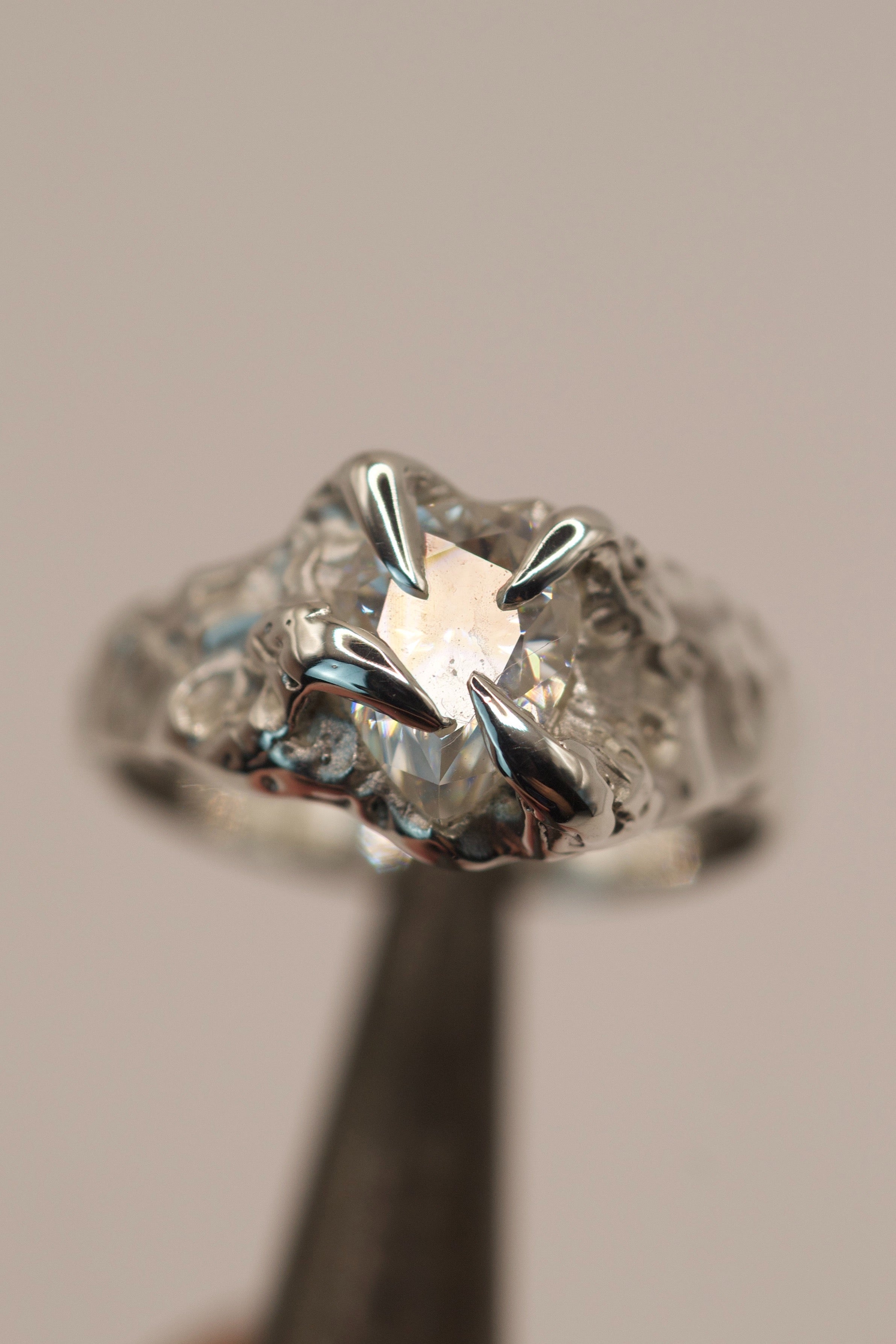 Handmade lost wax cast recycled sterling silver ring with organic molten claws holding a pear cut moissanite, ethereal ice-like alternative engagement ring made using the wax carving technique